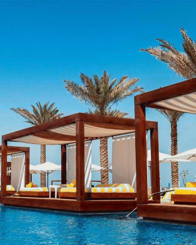 Cabanas along the edge of Emerald Pool, striped canvas overhead and yellow cushions on the daybeds, with the water directly below the decks